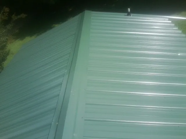 New green metal panels meeting at the ridge of a roof — Flat Roof Repair work by our crew in Orangeburg