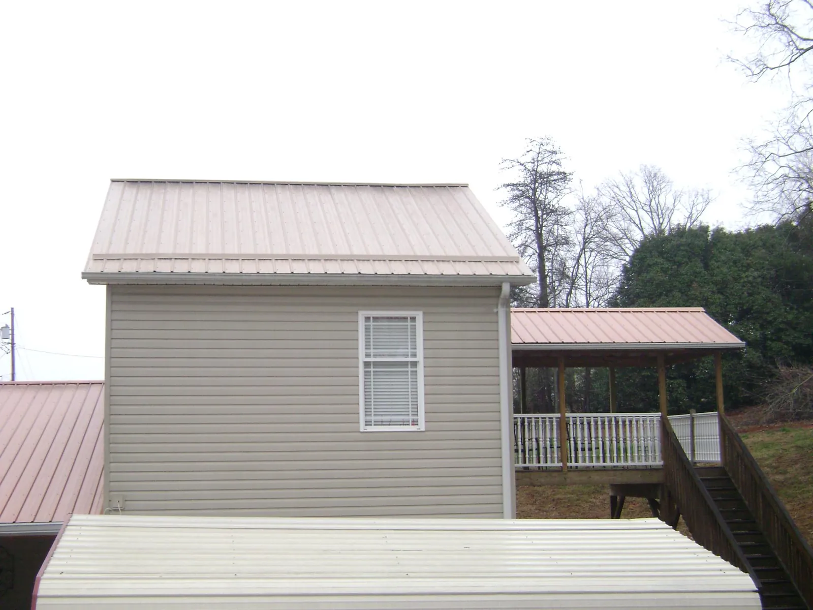 Tan metal roofs on a two story addition and attached porch, from a Roof Replacement job in Orangeburg